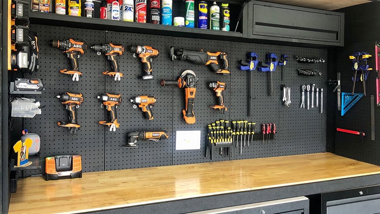 Black metal pegboard over workbench used to hold tools.